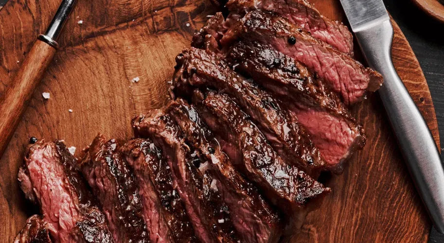 A grilled USDA Choice Delmonico Ribeye steak displayed on a cutting board, with a knife and fork positioned beside it.