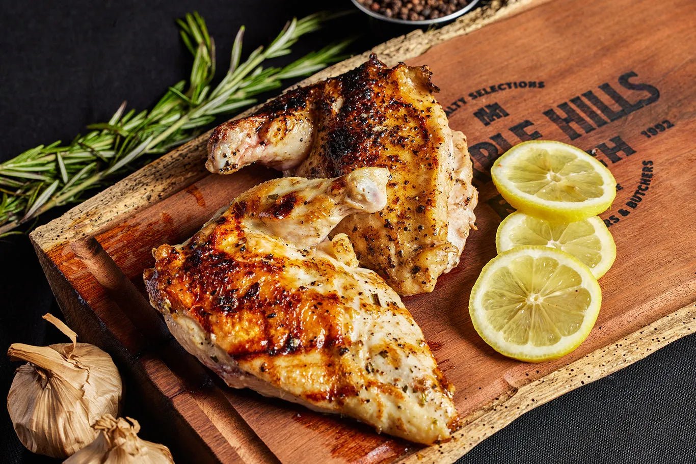 A serving of airline chicken with rosemary, elegantly arranged, with scenic hills in the background.