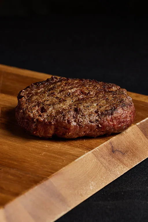 A grilled Black Angus burger placed on a wooden board.