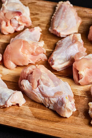 Raw chicken wings arranged on a wooden cutting board, ready for preparation and cooking.