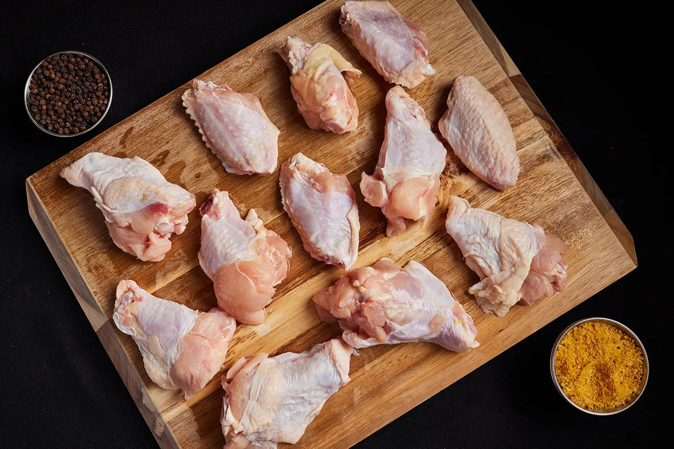 Raw chicken wings arranged on a wooden cutting board, ready for preparation and cooking with spices.