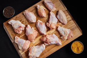 Raw chicken wings arranged on a wooden cutting board, ready for preparation and cooking with spices.