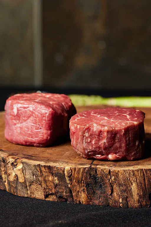 Two USDA Choice filet mignon steaks displayed on a wooden cutting board.