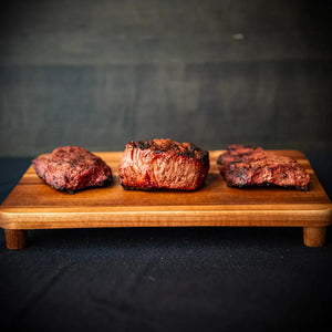 Three steak cuts on a wooden cutting board: Filet Mignon, Sirloin, and Flat Iron.