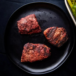 A black plate featuring three cuts of meat: Filet Mignon, Sirloin, and Flat Iron Steak.