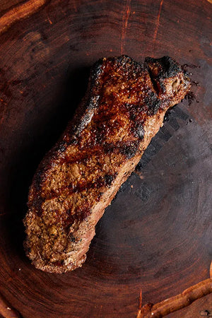 USDA Prime New York Strip steak displayed on a wooden board.