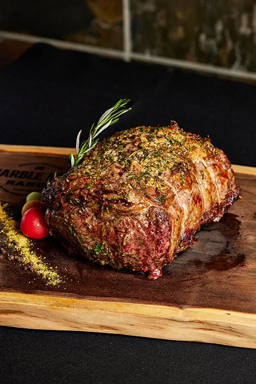 A boneless prime rib roast displayed on a wooden cutting board, showcasing its color and texture.