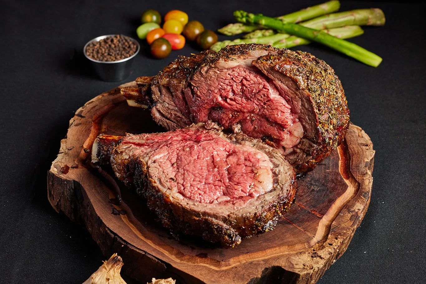 A 3-bone prime rib roast steak displayed on a wooden board, accompanied by a variety of vegetables.