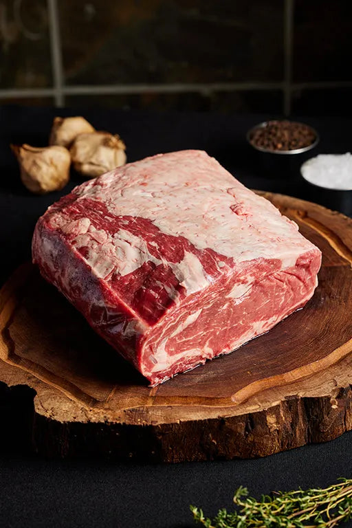 A large boneless prime rib roast resting on a wooden board, highlighting its color and marbling.