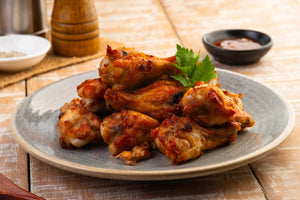 A plate of chicken wings garnished with herbs and served with sauce, ready to be enjoyed.