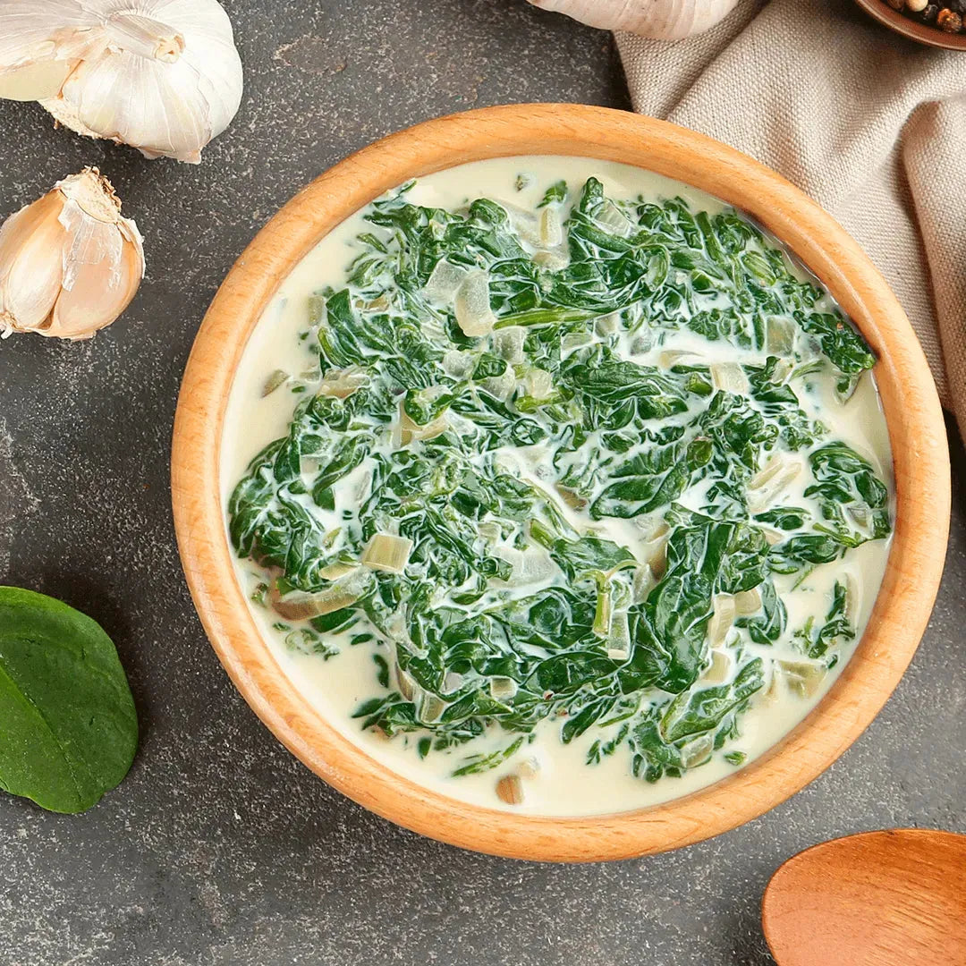 A bowl of creamed spinach soup garnished with garlic and spices.