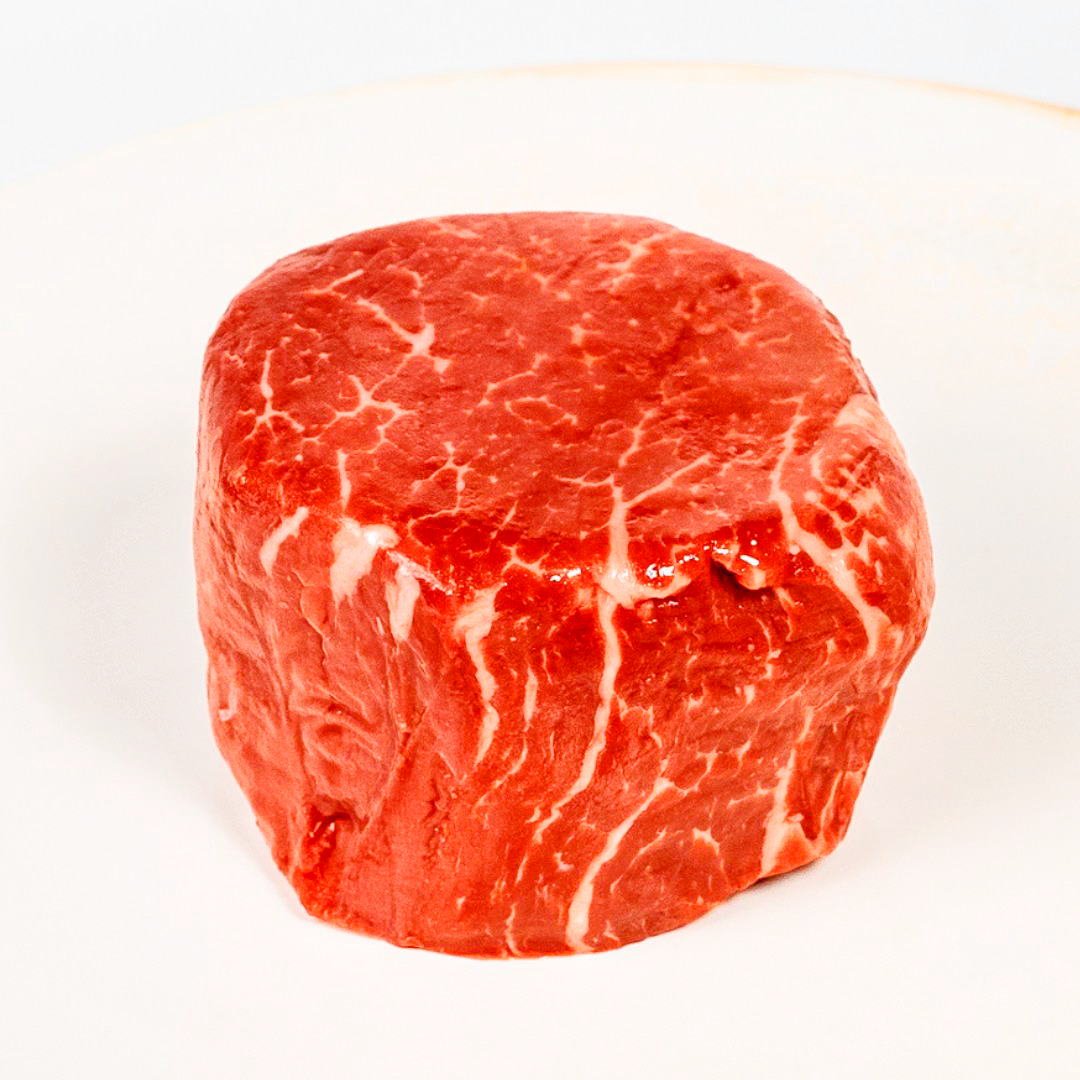 A filet mignon steak on a white plate.