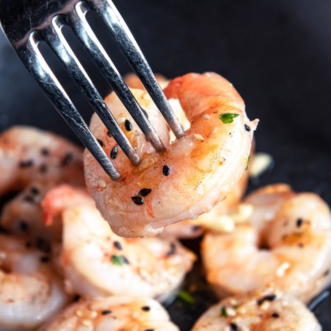 A fork holding a piece of delicious cooked shrimp.